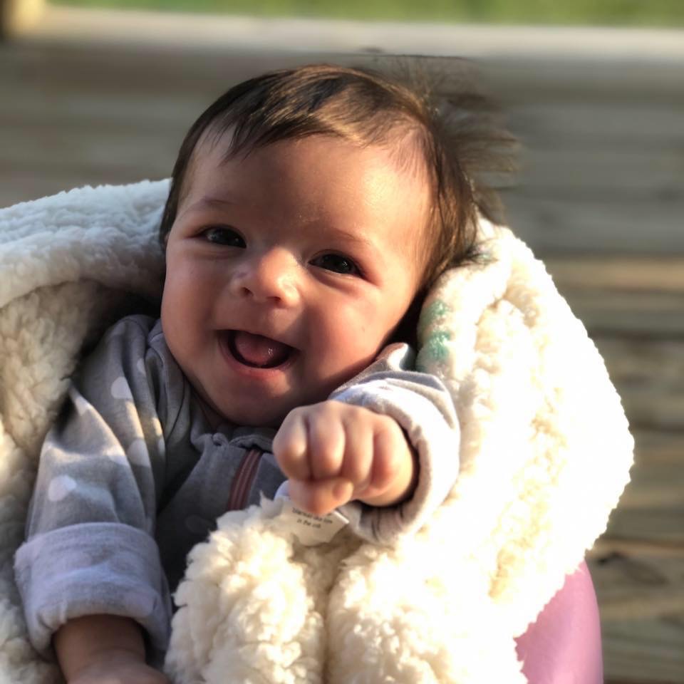 Photo of a smiling baby wrapped in a blanket.